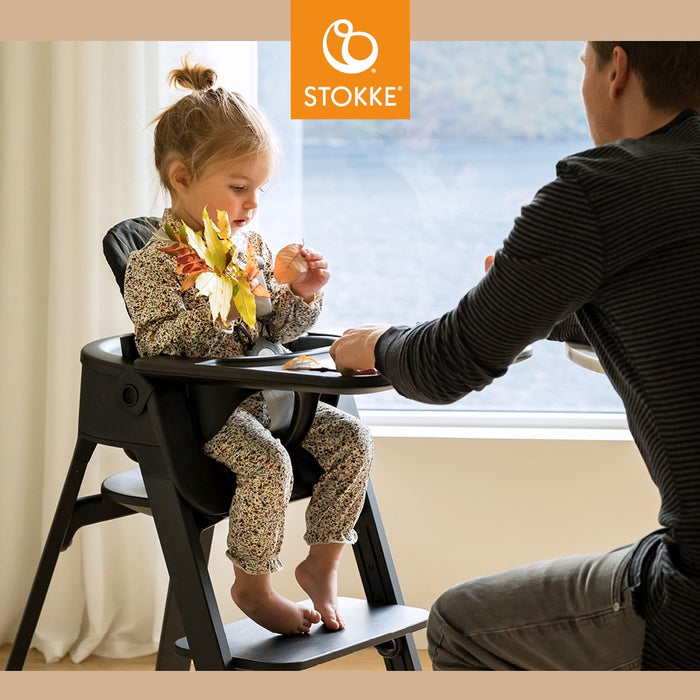 Little kid playing with fall leaves in Stokke Steps High Chair