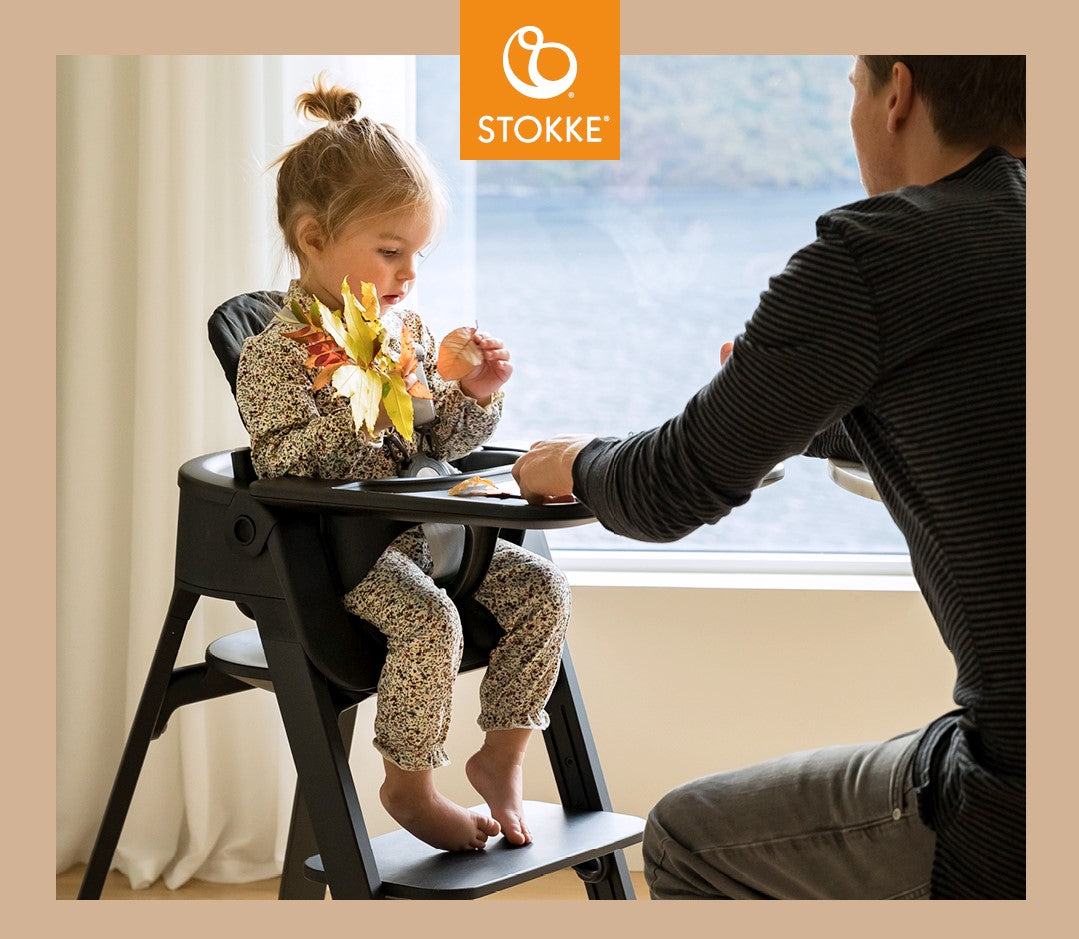 Little kid playing with fall leaves in Stokke Steps High Chair