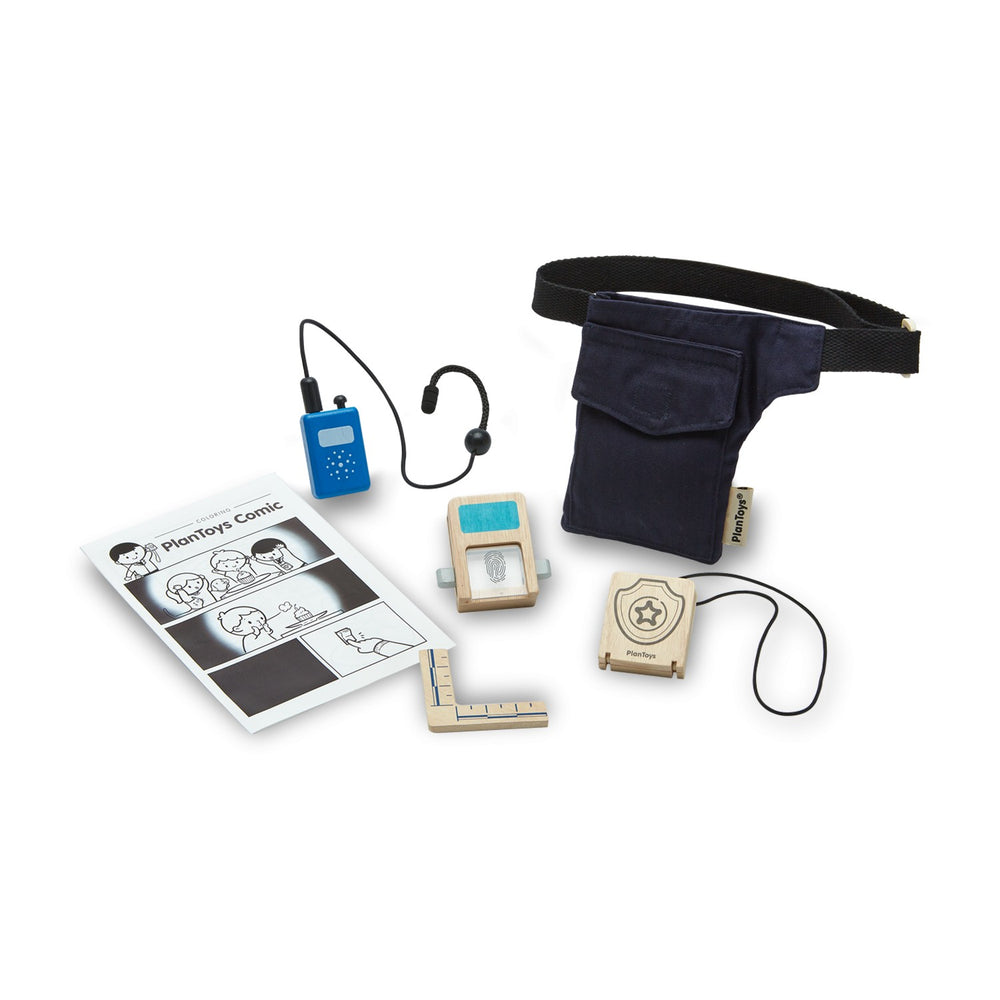 plan toys secret agent play set, all items laid out on a white surface. Utility belt, wood badge, thumbprint reader, ruler, walkie talkie, Plantoys sppy comic