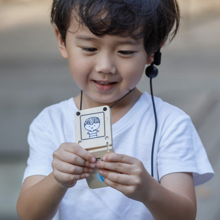a cute toddler using the plan toys secret agent walkie talkie